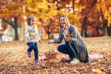 Mother and daughter in the park enjoying the beautiful autumn nature.