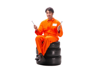 Young garage worker with tyre isolated on white