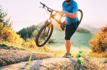 Canvas Print -  Cyclo-cross competition member Man mountain biker carrying his bike up on hill top