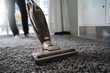 Close-up  man using a vacuum cleaner while cleaning in the room
