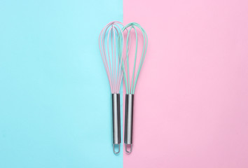 Two whisk on blue pink pastel background. Top view, minimalism.