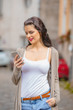 © astrosystem - Cute young woman using cellphone in urban surroundings.