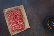 © happyimages - Fresh raw grass fed angus ground beef on parchment paper, concrete rustic background, blank space, top view