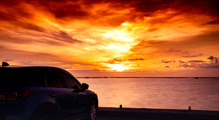 Wall Mural - Blue compact SUV car with sport and luxury design parked on concrete road by the sea at sunset. Electric car technology and business. Hybrid auto and automotive. Tropical road trip travel. Automotive