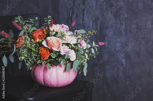 Obraz na PCV Autumn floral bouquet in colored pumpkin vase on black chair, copy space