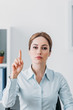 © LIGHTFIELD STUDIOS - serious adult businesswoman looking at camera and pointing up at office