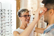Attractive young couple in optical store buying glasses and smiling
