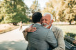 © bnenin - Elderly father and adult son hugging in the park.