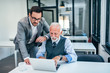 © bnenin - Young man working with boss or older employee in the office.