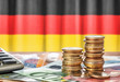 Geldscheine und Münzen vor der Nationalflagge Deutschlands