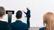 © LIGHTFIELD STUDIOS - smiling handsome african american speaker talking during seminar in conference hall and pointing on screen