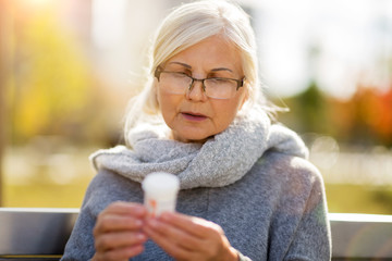 Senior woman taking prescription medicine outdoors
