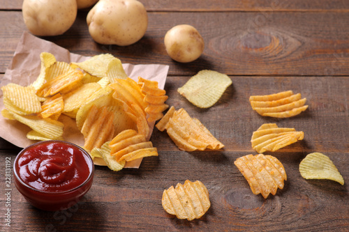 Valokuva Chips with red sauce and fresh potatoes on a brown wooden table