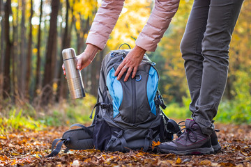 Wall Mural - traveler is taking thermos out from her backpack. woman is wearing hiking boot and standing on footp