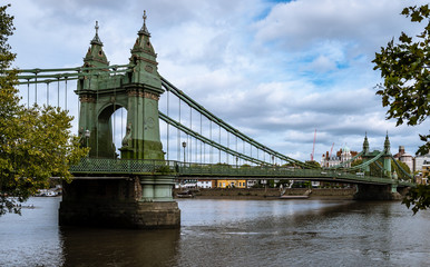 The Hammersmith Bridge, a suspension bridge that crosses the River Thames in west London. Hammersmith is in the background, photo taken from Barnes.