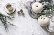 Autumn styled photo. Feminine Halloween desktop scene. Cup of coffee, eucalyptus, pine cones, white pumpkins and gypsophila flowers. Table background. Thanksgiving. Flat lay, top view.
