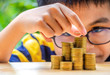 The Asian boy stacking with coins to save the money for the future. Concept for loan, property ladder, financial, mortgage, real estate investment, taxes and bonus.