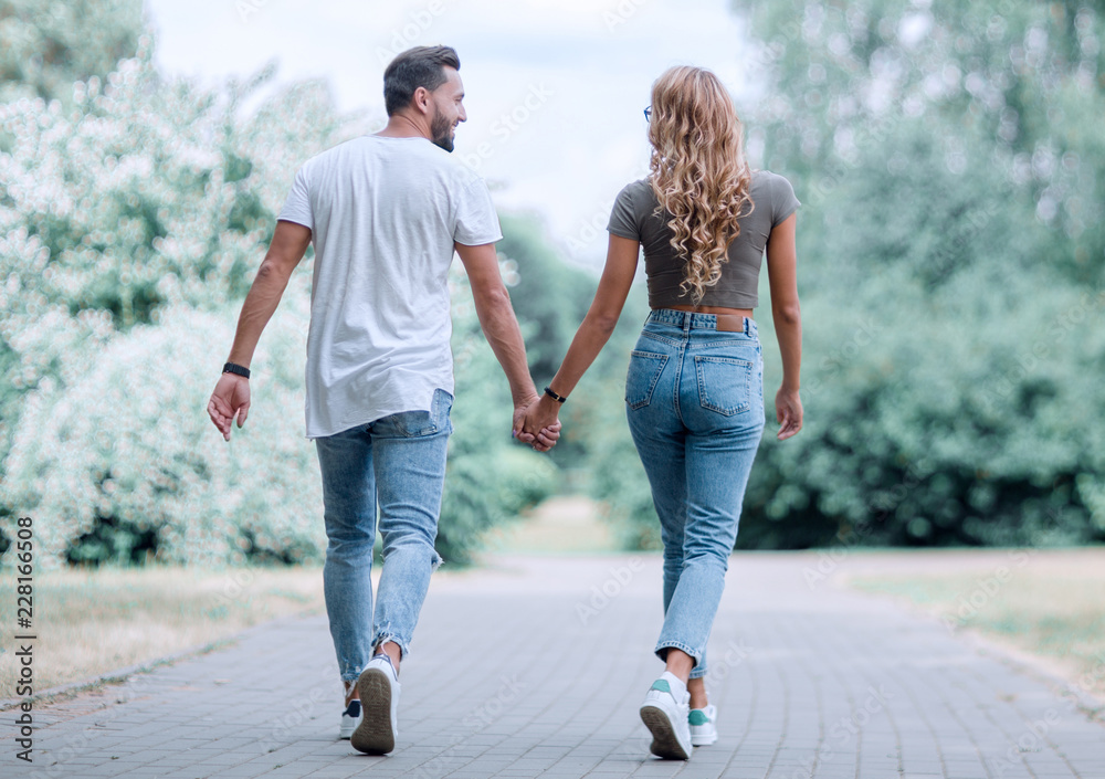 Couple in love walking in park holding hands - obrazy, fototapety, plakaty 