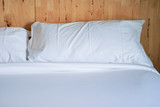 Fototapeta  - White pillow on bed with wooden wall.