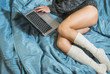 A young girl with sexy legs in a warm sweater lying on the bed with a laptop. Work at home