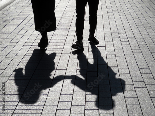 Silhouette of love couple on the street. Two people walking and holding each other\'s hands, shadows on pavement, concept for romantic love, family or friendship