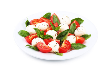 Mozzarella, tomatoes and basil leafs on plate isolated on white background