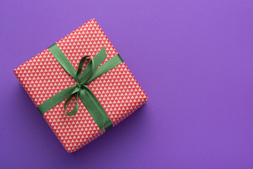 Wall Mural - Wrapped gift box with colored ribbon as a present for Christmas, new year, mother's day, anniversary, birthday, party,  on violet background, top view. Present for a colleague at work.