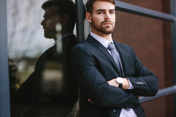 Wall Mural - Portrait of confident businessman standing by office building