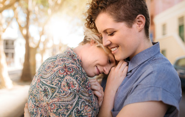 Smiling young lesbian couple sharing an affectionate moment together outside