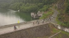 Aereial Panoramic View Of A Group Of Cyclists Peddling Over The Dam At Colibita Lake During Tura Cu Copaci Race