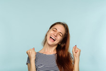 Yes Success And Achievement. Happy Joyful Smiling Girl Making A Win Gesture. Excited Thrilled Woman Portrait On Blue Background.