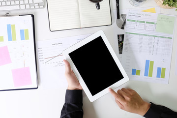 Businessman using mockup tablet on office desk with finance paper report and top view.