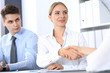 © rogerphoto - Business handshake by blonde woman and her partner at meeting. Concept of success and agreement