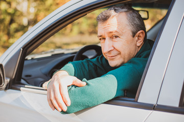 Portrait Of A Happy Mature man Driving Car To Go To Work or travels. Concept of automobile and popular hobby  