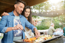 Couple Preparing Summer Barbecue For Friends