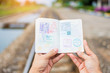 Hand holding passport show immigration stamps on passport with railway background. subject is blurred.