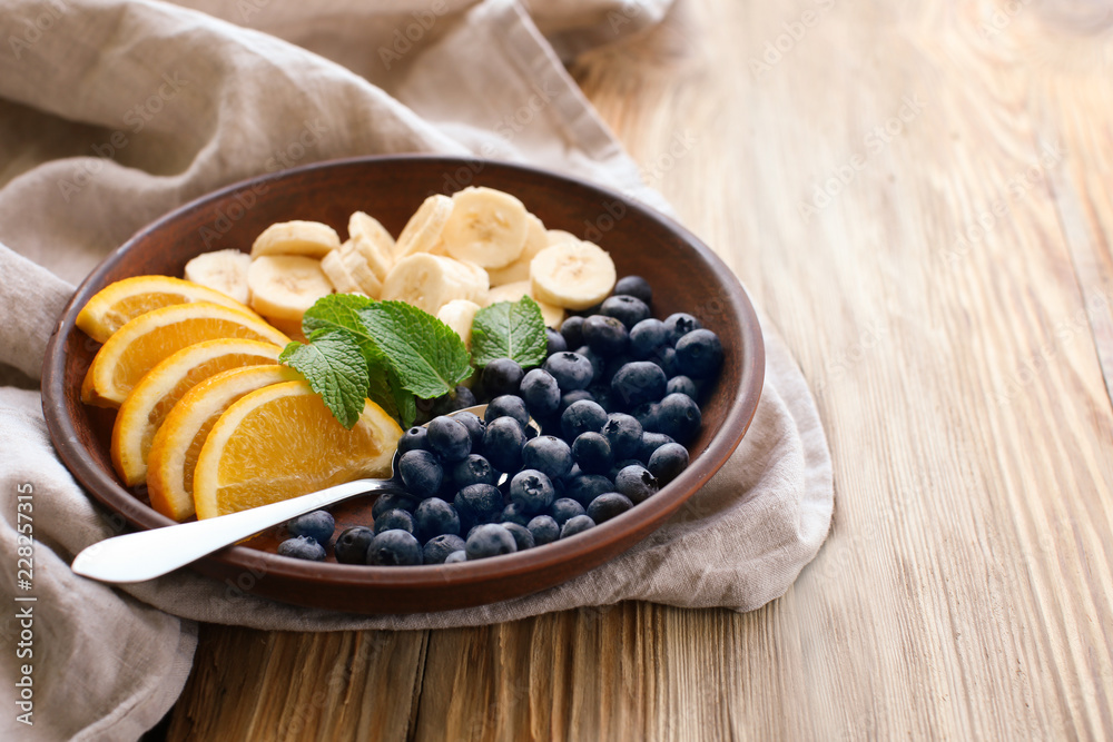 Plate with delicious fruit salad on wooden table