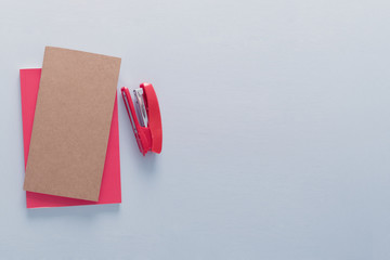 Two workbooks and a stapler placed from the right side of a grey background. Back to school concept. Office supplies flat lay