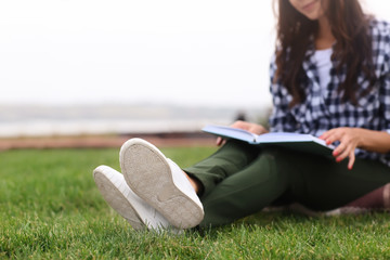 Sticker - Young woman with book resting on green grass outdoors