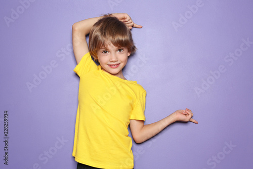 Cuadros en Lienzo Little boy in t-shirt pointing at something on color background