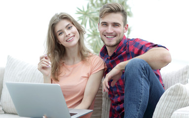 Poster - young couple of students with laptop sitting on the couch