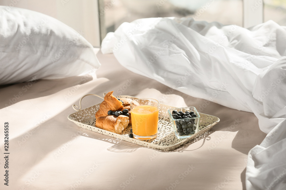 Tray with delicious breakfast on bed