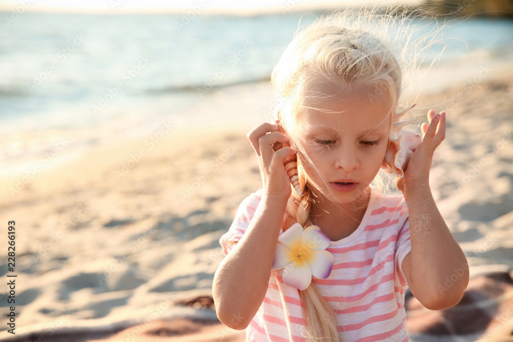 Cute little girl with sea shell on beach