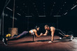 © LIGHTFIELD STUDIOS - athletic sportsman and sportswoman doing push ups together and holding hands in dark gym