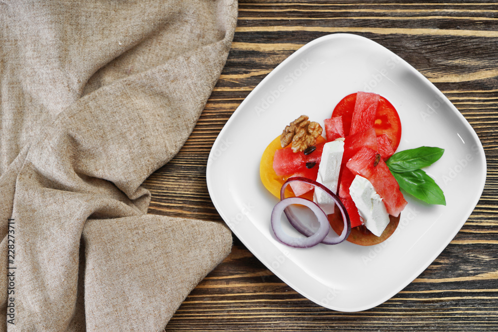 Plate with delicious watermelon salad on wooden table, top view