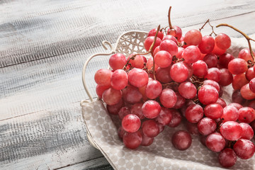 Tray with red grapes on wooden table, closeup