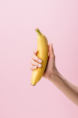 Wall Mural - cropped shot of woman holding banana isolated on pink