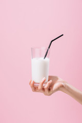 Wall Mural - cropped shot of woman holding glass of milk isolated on pink