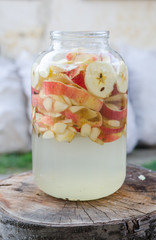 Wall Mural - Apple vinegar making - apple pieces floating in a glass in rustic interior