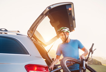 Wall Mural - Man taking his bicycle out from the trunk of a car. Sport leisure concept image